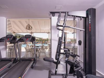 Modernes Fitnessstudio mit Laufbändern und Krafttrainingsgeräten vor bodentiefen Fenstern.