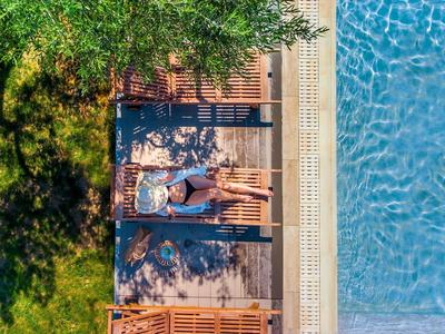 Deux chaises longues à côté d'une piscine avec des arbres verts à l'ombre.