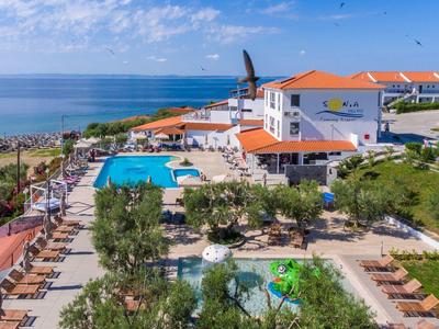 Hotelanlage mit Pools, Sonnenschirmen und direktem Meerblick unter blauem Himmel.