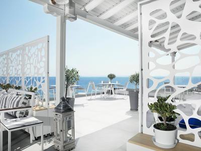 Modernes, helles Hotelzimmer mit Blick auf das Meer und weißen Möbeln.