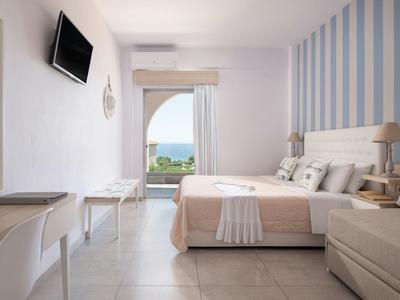 Modernes, helles Schlafzimmer mit Doppelbett, Meerblick, Wand-TV und gestreifter Akzentwand.