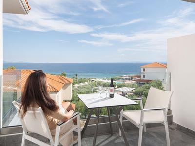 Balkon mit Meerblick, Tisch, zwei Stühle, Wein und Glas, entspannte Atmosphäre.