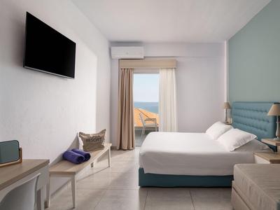 Modernes Hotelzimmer mit Bett, Fernseher und Balkon mit Meerblick.