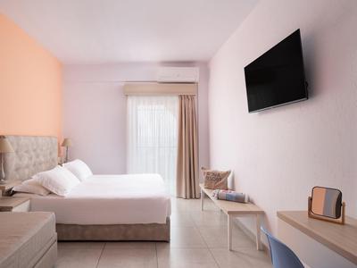 Helles Hotelzimmer mit Doppelbett, Wand-TV und Zugang zum Balkon durch Glas-Schiebetür.