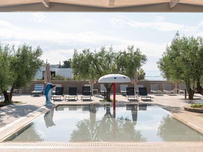 Moderner Pool mit Sonnenliegen und Olivenbäumen in einem ruhigen Hotelgarten.