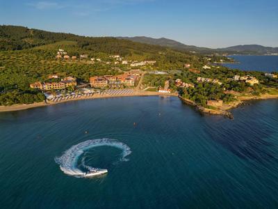Luftaufnahme eines Küstenresorts mit Sandstrand und Jetboot auf dem Wasser.
