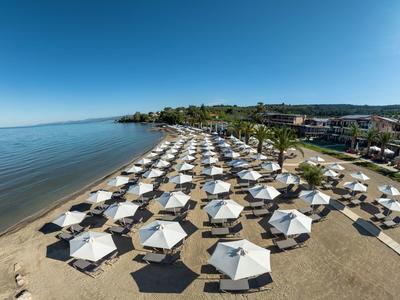 Strand mit Reihen von weißen Sonnenschirmen und klarem blauem Himmel am Meer