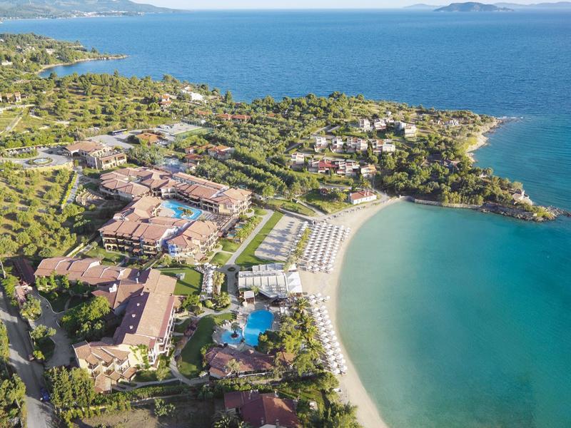 Luftaufnahme eines Resorts mit Strand, Pools und üppiger Vegetation an der Küste