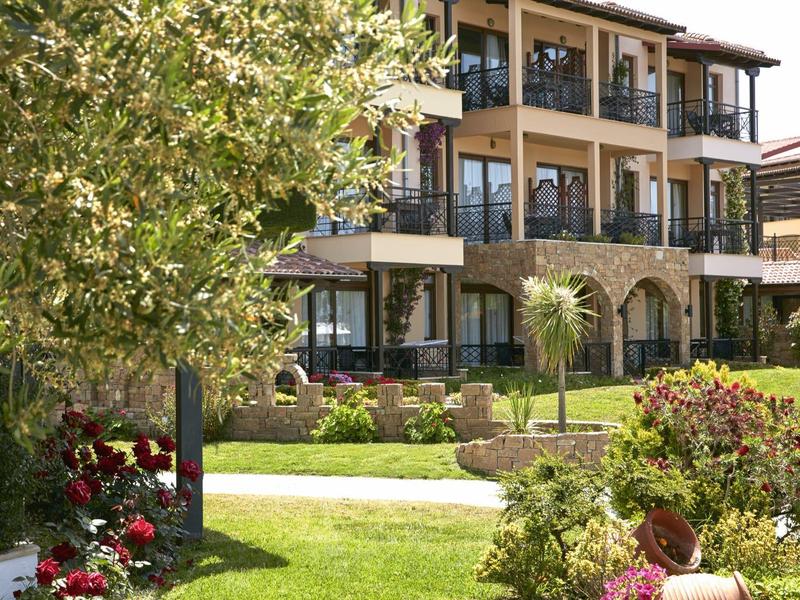 Mehrstöckiges Hotel mit Terrasse und Garten voller Blumen und Bäume bei Sonnenschein