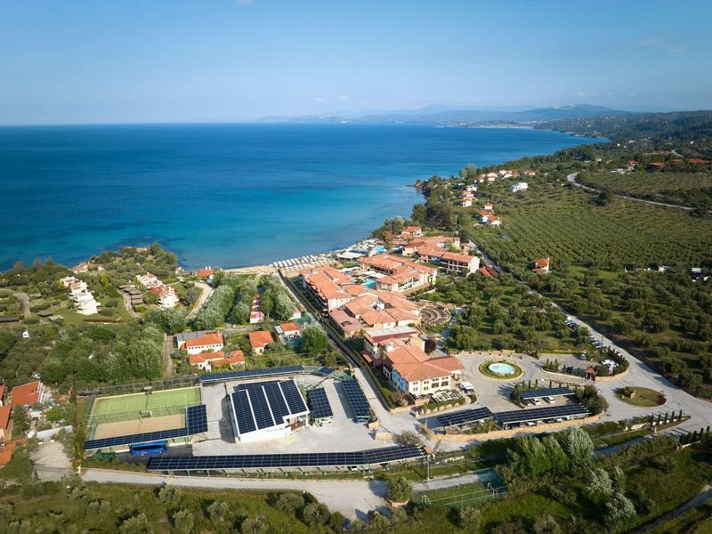 Luftaufnahme eines Küstendorfs mit Gebäuden, Straßen und grüner Landschaft am Meer.