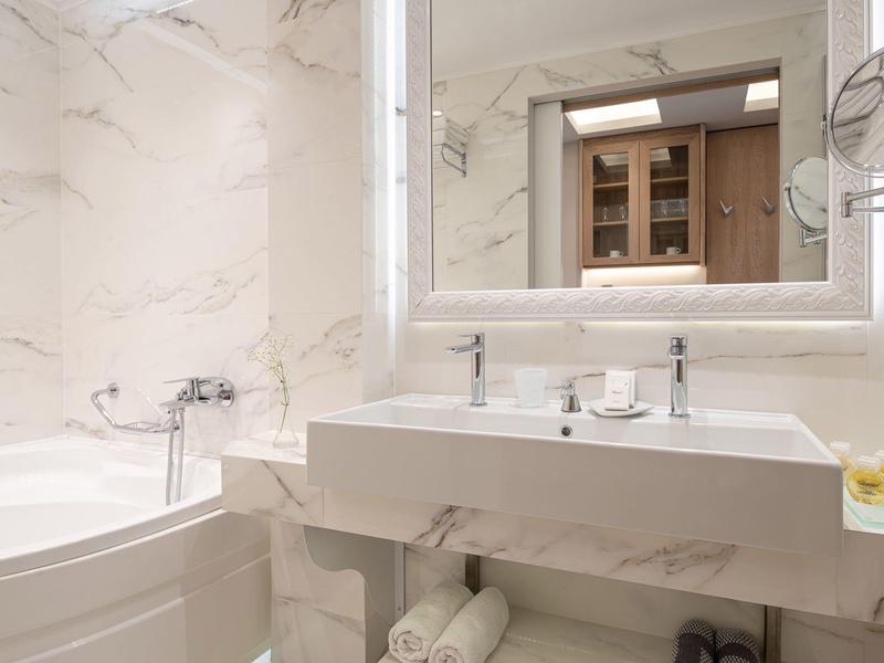 Modernes Badezimmer mit Marmorwaschbecken, beleuchtetem Spiegel und Badewanne.