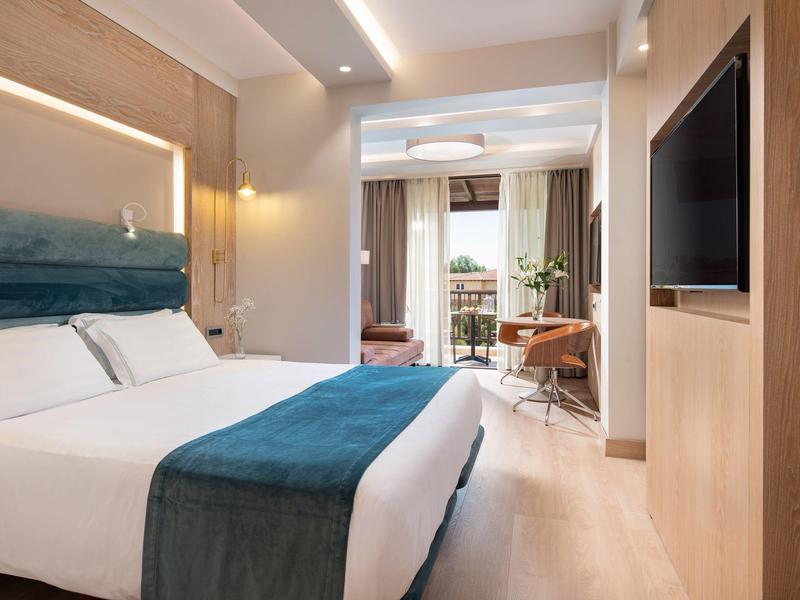 Modernes Hotelzimmer mit Doppelbett, Balkon und heller, einladender Einrichtung.