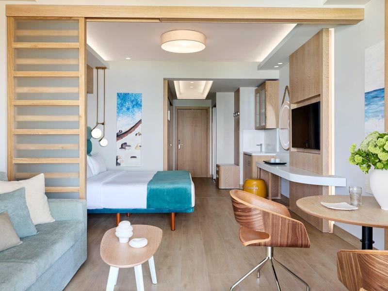 Modernes, helles Hotelzimmer mit Holzfußboden, Sitzbereich und Arbeitsplatz.