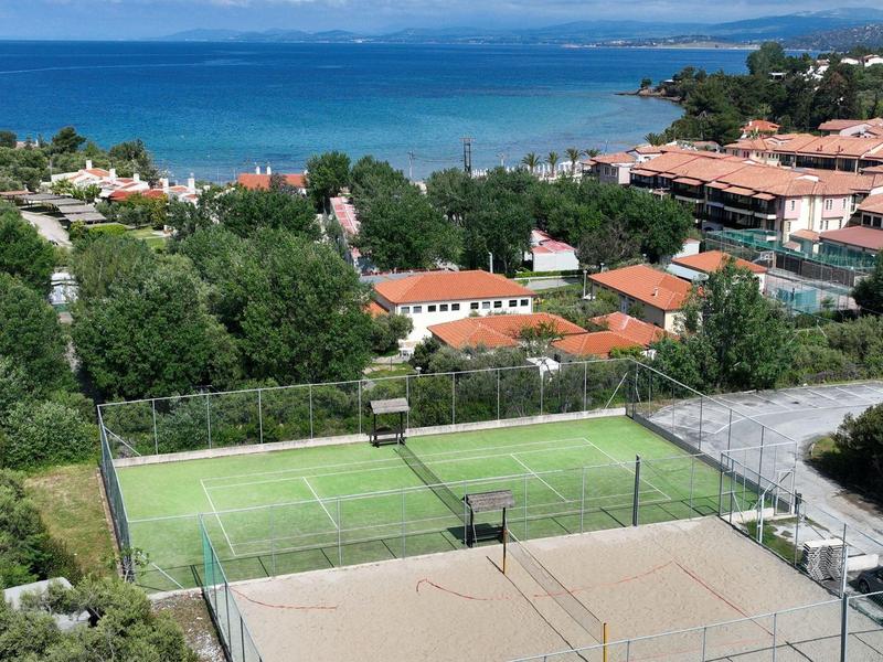 Blick auf Tennisplatz mit grünem und sandfarbenem Belag nahe Küste und Hotelgebäuden