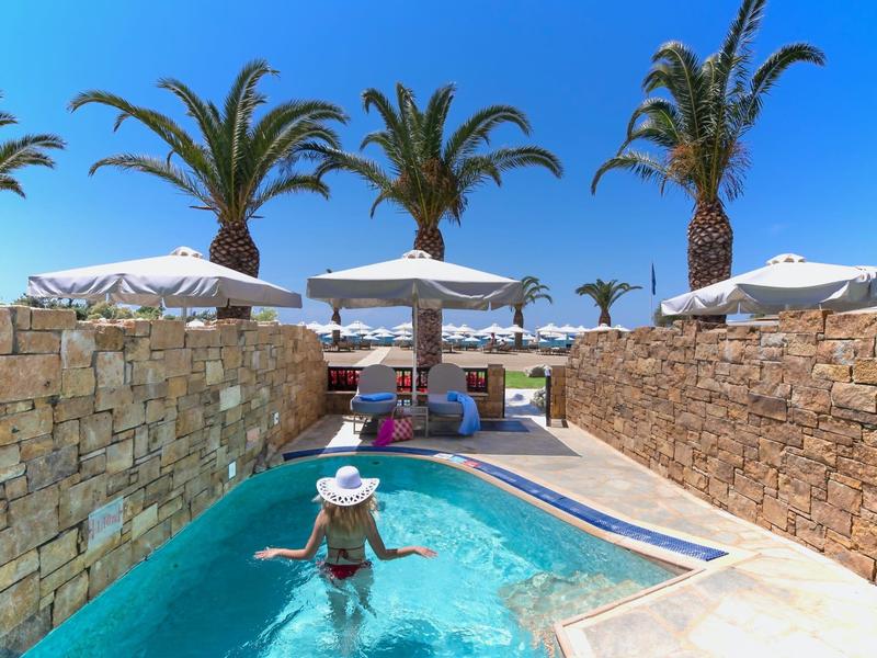Frau in Pool mit Blick auf Palmen, Sonnenschirme und klares blaues Himmel am Hotel