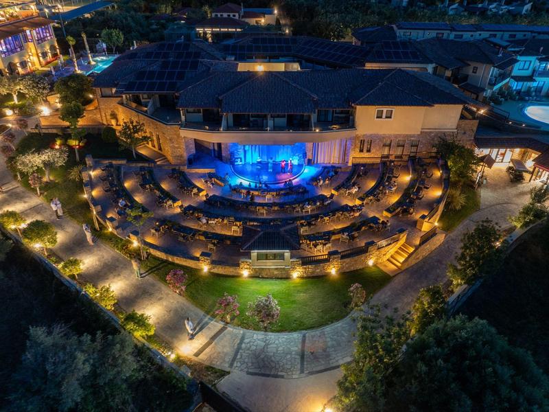 Beleuchtetes Hotel mit terrassenförmigem Außenbereich und Garten in der Nacht