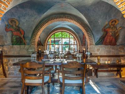 Cozy restaurant with wooden furniture and murals in a vaulted stone building.