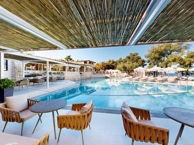 Area piscina moderna con posti a sedere e ombra in un complesso alberghiero.