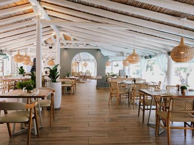 Helles, luftiges Restaurant mit Holzdecke, Holzboden und vielen Tischen und Stühlen.