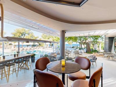 Moderner Hotel-Loungebereich mit runden Tischen, bequemen Stühlen und Blick auf den Pool.