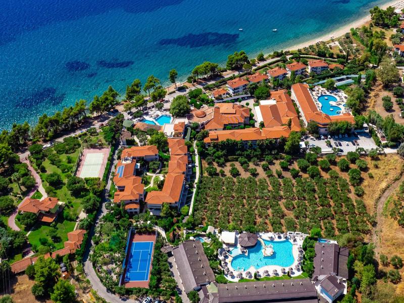 Aerial view of a resort with multiple pools, tennis courts, and direct sea access.