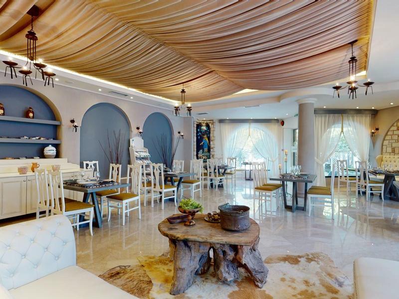 Bright, elegant hotel dining area with white furniture and decorative ceiling drapes.