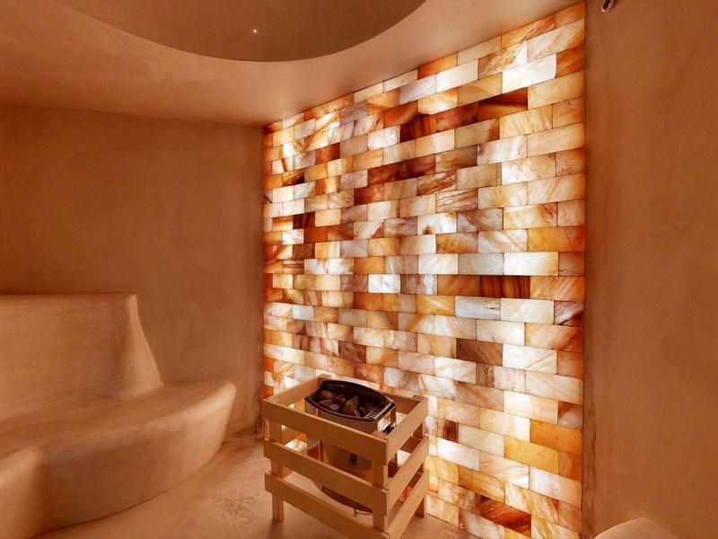 Wellness area with salt wall and bench under warm lighting.