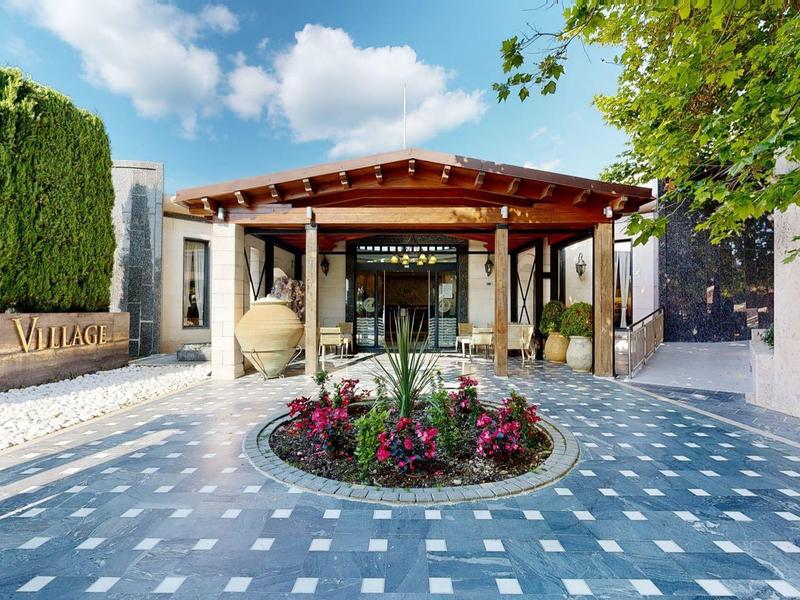 Hotel entrance with covered area, flower bed, and parking spaces.