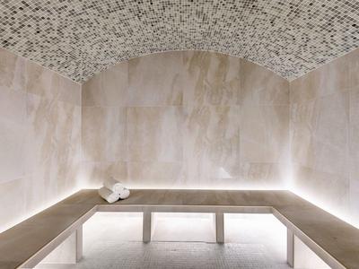 Salle de vapeur moderne avec murs carrelés beige, banc intégré et plafond à motif de galets.
