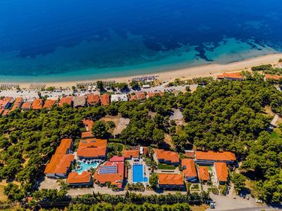 Vue aérienne d'une station balnéaire avec des bâtiments au toit rouge et des piscines entourées d'arbres.