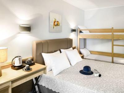 Chambre d'hôtel confortable avec lit queen, lits superposés en bois, table de chevet et éclairage doux.