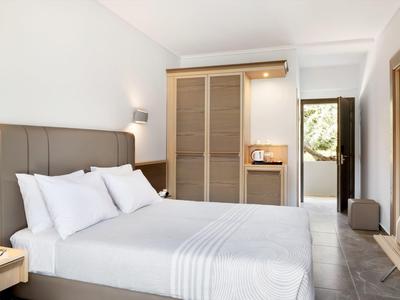 Chambre d'hôtel lumineuse avec un lit double, une armoire et une porte vers l'extérieur.