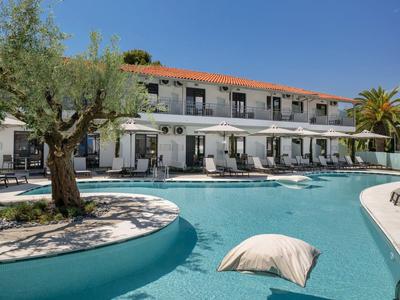 Piscine extérieure avec coussin devant un bâtiment d'hôtel de deux étages sous un ciel dégagé.