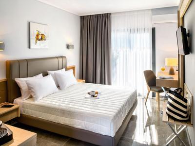 Modern hotel room with double bed, desk, chair, and balcony door with curtains.