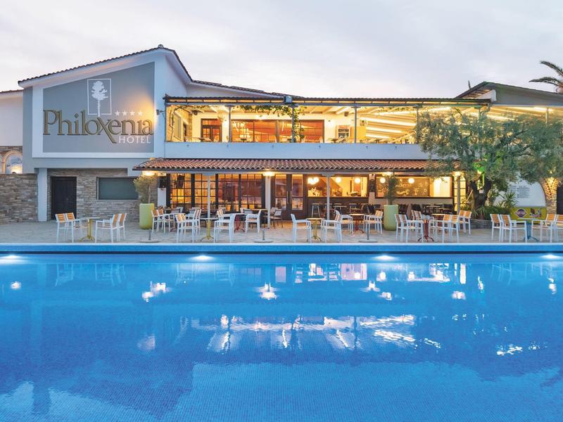 Hôtel moderne avec grandes fenêtres éclairées et grande piscine extérieure au crépuscule