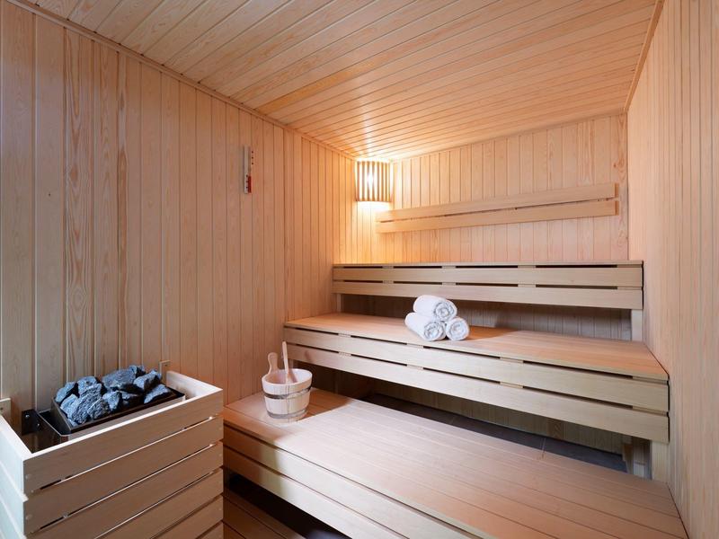 Intérieur d'un sauna en bois avec des bancs en bois, un seau et des serviettes pliées.