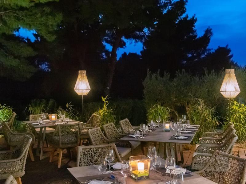 Terrasse de restaurant extérieure la nuit avec lanternes allumées et chaises confortables.