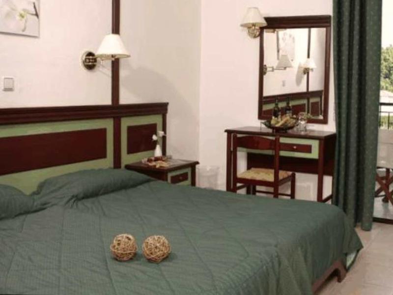 Habitación de hotel con cama doble, escritorio con espejo y balcón con sillas y mesa.