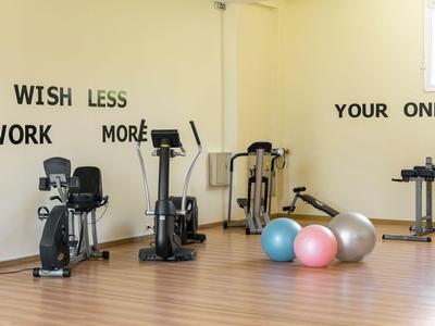 Salle de sport avec équipements d'entraînement et ballons de gym colorés sur murs clairs et sol en bois.