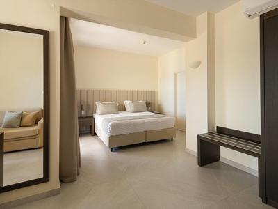 Světý hotelový pokoj s manželskou postelí, velkým zrcadlem a moderní skříní v neutrálních tónech.