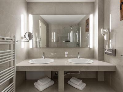 Moderní koupelna s dvojitými umyvadly, velkými zrcadly a sušáky na ručníky.