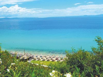 Pohled na pláž s lehátky, modré moře a zatažená obloha.