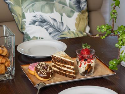 Gâteau, dessert et assiettes sur une table en bois avec des coussins en arrière-plan.