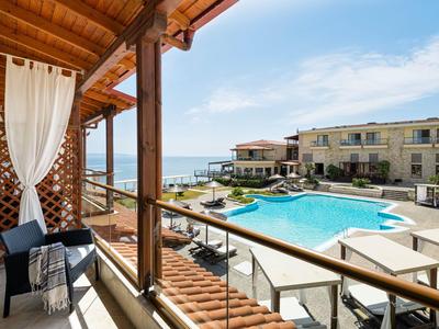 Balcon avec coin salon offrant vue sur la piscine et la mer dans un complexe hôtelier.