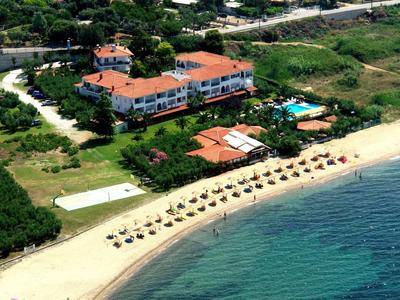 Complesso alberghiero con tetti rossi, piscina e spiaggia con ombrelloni vicino al mare limpido.