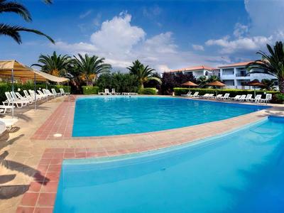 Grande piscina dell'hotel con lettini e palme sotto un cielo azzurro.