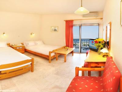 Camera d'hotel luminosa con due letti, balcone e vista mare.