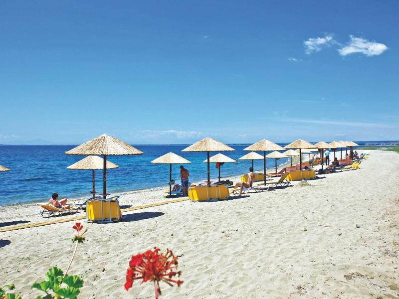 Spiaggia con ombrelloni e sdraio sul mare sotto un cielo azzurro.