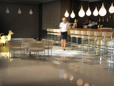 Moderne Bar mit hoher Theke, weißen Hockern, Tropfenlampen und goldfarbenem Rentier-Dekoobjekt.