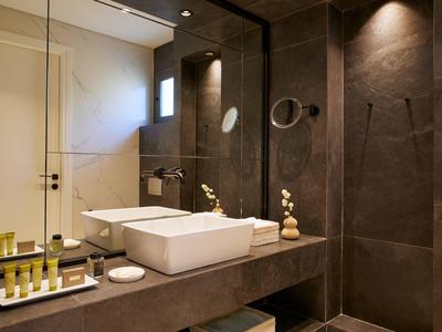 Modernes Badezimmer mit dunklen Fliesen, großem Spiegel und weißem Aufsatzwaschbecken.